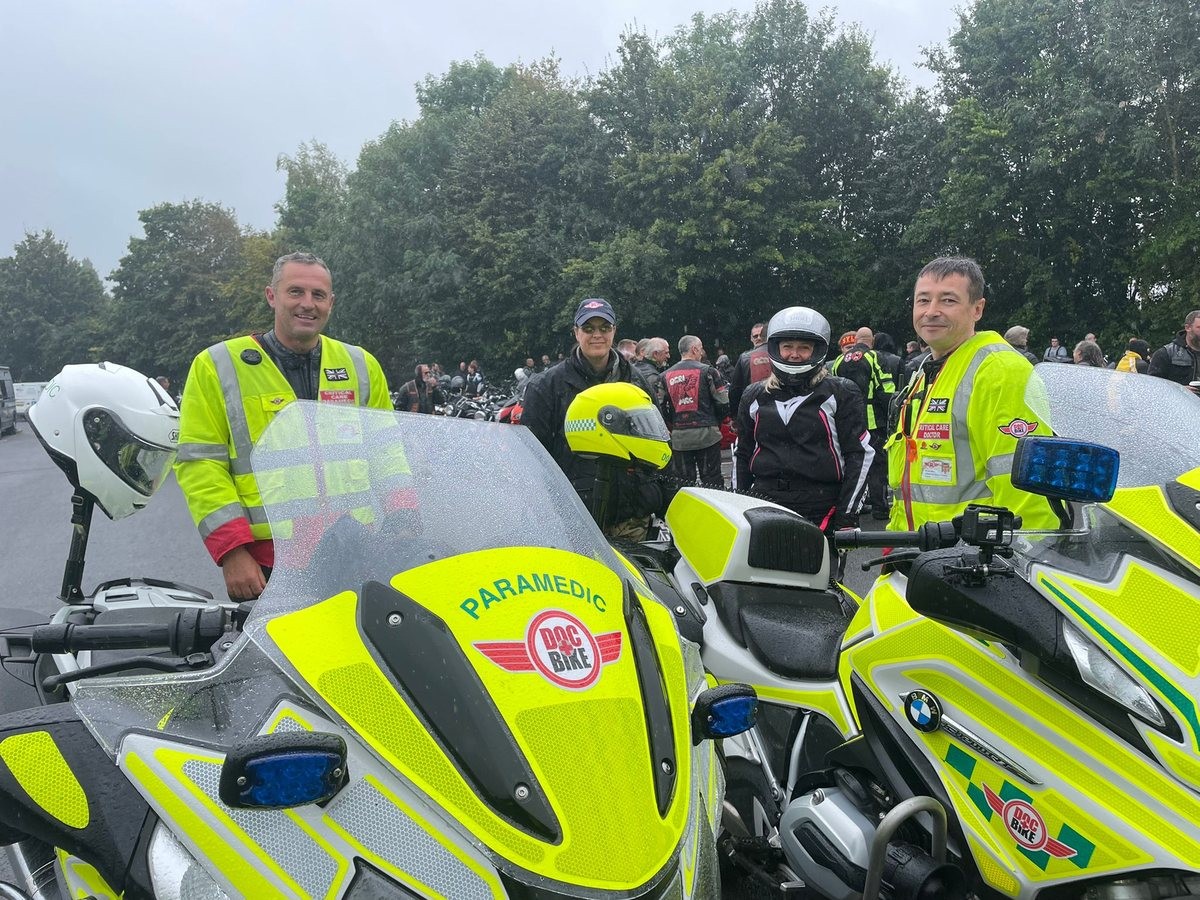 DocBike clinicians and riders meeting motorcyclists beside marked DocBike motorcycles.