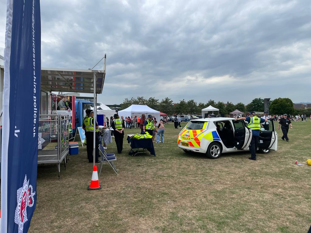 Field containing a police car and police officers next to stands